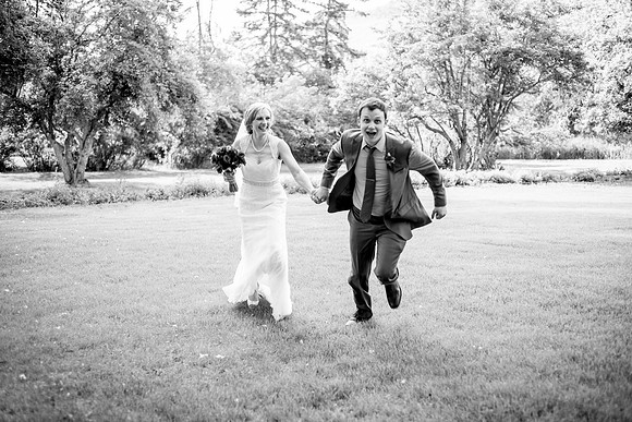 Super happy groom pulling his bride through the grass at the Bow Valley Ranche in Calgary, Alberta.
